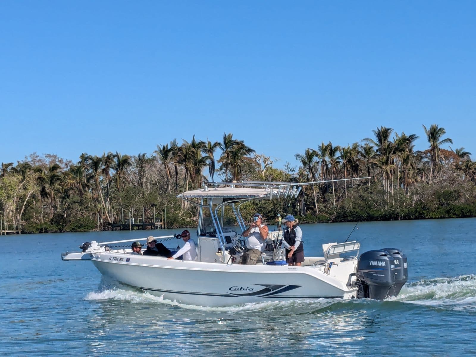 A Venice Reef Charters trip underway on the Intracoastal near Nokomis, guests aboard, outriggers up, mangrove shoreline behind them.